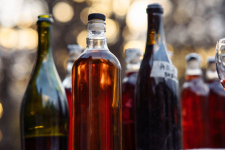 Close - up of group of glass transparent and dark bottles with corks of homemade berry, fruit wine stands against background of sunset. Homemade wine. Natural products. National alcoholic beverages.の写真素材