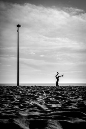 Happy child jumping and playing on the beach with a beautiful sunset in France on the Atlantic coastの写真素材