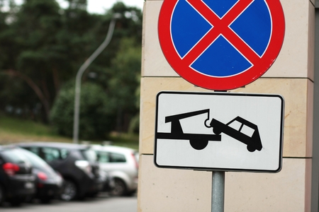 road sign - no parking, and cars will be towed away and parked cars in the backgroundの写真素材