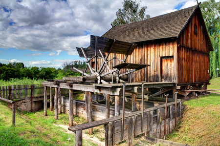 old wooden historic water mill standing on a small streamの写真素材