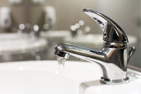 The white bathroom classic tap pouring out of it, clean waterの写真素材