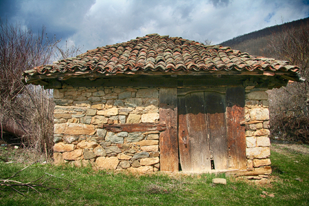 small stone cottage covered with a red tiled roof with old wooden doorsの写真素材