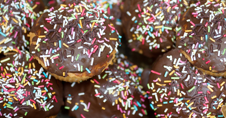 Delicious donuts covered with chocolate and sprinkled with different colored sugar sticks