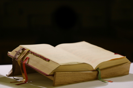Liturgical book with colored tabs lying on a wooden stand on a white tableclothの写真素材