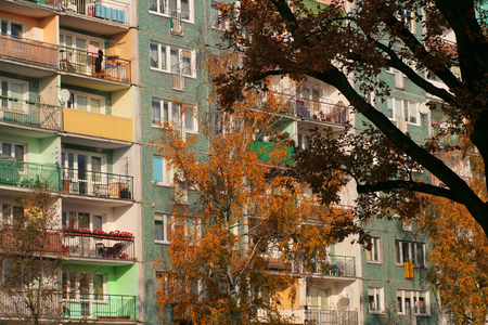 Balconies and windows in a multi-family house (block) and an autumn treeの写真素材
