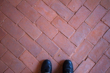 Old floor in historic castle stacked with red brick and black leather shoesの写真素材