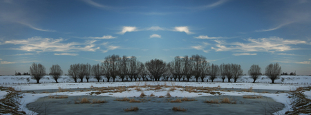 Panorama of river bank in winter with snow, ice and willowsの写真素材