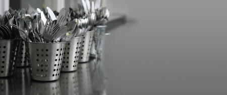 cutlery (knives, forks, spoons) in metal containers on a gray countertopの写真素材