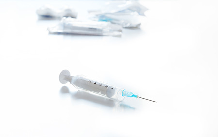 Syringe lying on a white table with other syringes and packagingの写真素材
