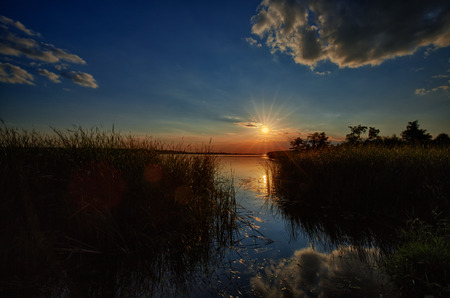 Sunset on Zegrzynski lake with reeds and sun and cloudsの写真素材
