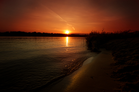 Sunset on the lake ZegrzyÅski with a sandy beach washed by the waves of the lakeの写真素材