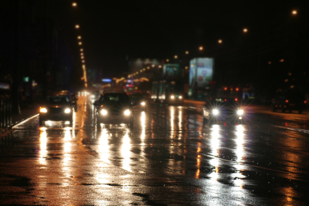 Riding cars at night in a city where it was raining, reflections of lights on a wet roadwayの写真素材