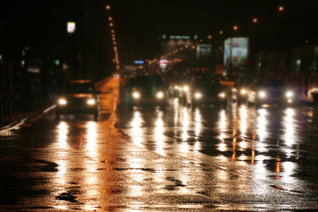 Riding cars at night in a city where it was raining, reflections of lights on a wet roadwayの写真素材