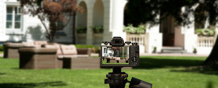 Camera and Garden furniture rattan, brown standing on the green grass in front of the buildingの写真素材