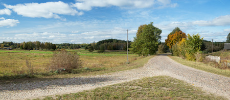 Crossing the old stone country road, you can see fields, a fence, a pillar and a nice blue sky with white clouds - Podlasie, Polandの写真素材