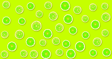 Background with green, fresh lemons on a lime color backgroundの写真素材