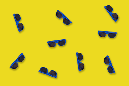 Blue sunglasses lying on a yellow like seaside sand backgroundの写真素材