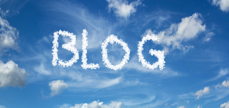 BLOG inscription painted with clouds on a blue background with white cloudsの写真素材