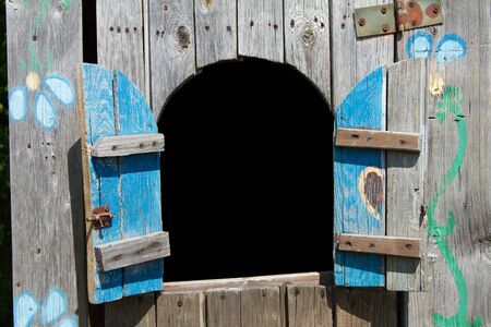 A wooden, big, old house for children to play, colorful with a window and shuttersの写真素材