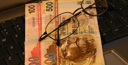 Hong kong dollars on a laptop keyboard with glasses