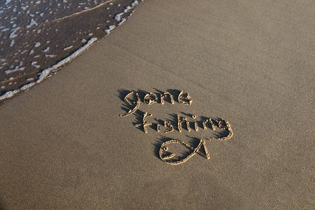 Gone fishing written in the sand at the beach with a small wave lapping at the edge of the scene.の写真素材