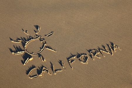 california written in the sand at the beach with sun symbol. 