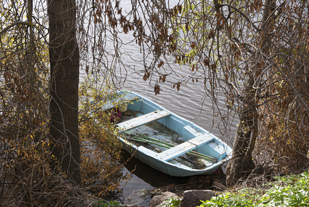 Blue boat on the lake in autumn forestの写真素材