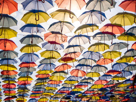 Colorful umbrellas hanging overhead over a blue sky