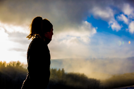 A female trail runs in the fog and snow of winter.