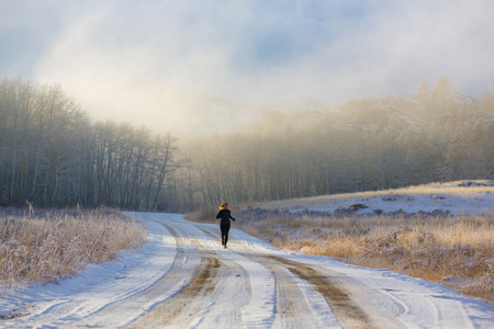 A female trail runs in the fog and snow of winter.の写真素材