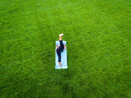 An aerial image of a woman doing yoga in a field of grass.の写真素材