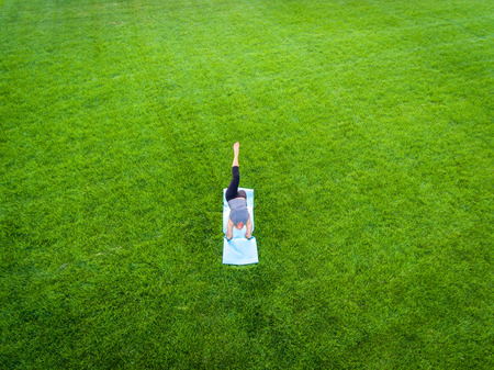 An aerial image of a woman doing yoga in a field of grass.の写真素材
