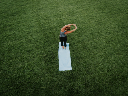 An aerial image of a woman doing yoga in a field of grass.の写真素材