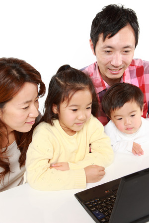 Japanese family of four on laptop computerの写真素材