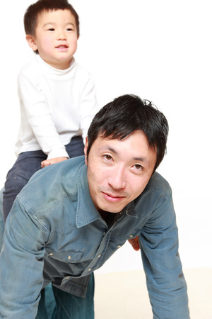 Japanese father and his son play horse-rideの写真素材