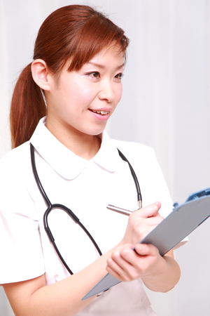 young Japanese nurse fills medical chartの写真素材