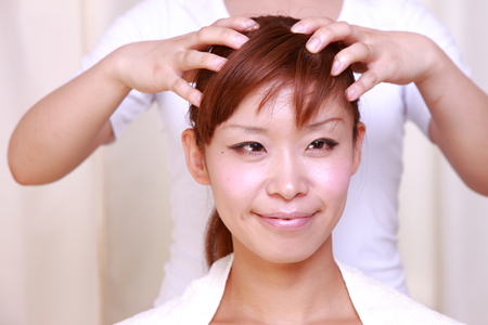 young Japanese woman getting a head massageの写真素材