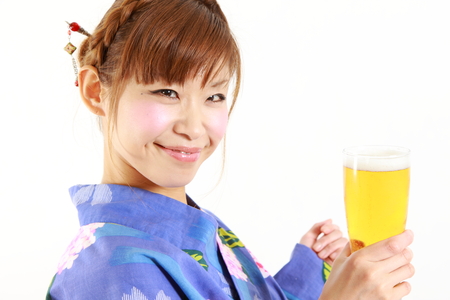 Young woman wearing Japanese kimono with a glass of beerの写真素材