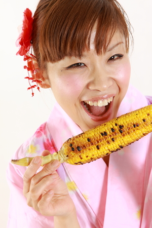 Young woman wearing Japanese kimono with grilled cornの写真素材