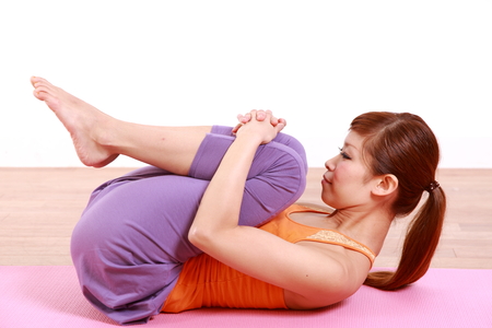 young Japanese woman doing YOGA wind relieving poseの写真素材