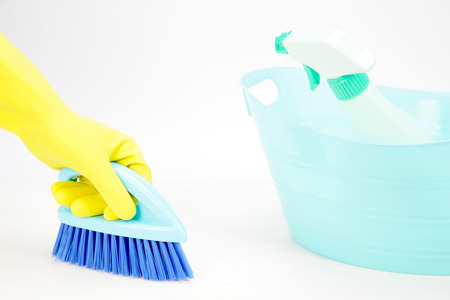 hand with glove using cleaning brush to clean up the floor