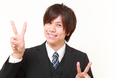 young Japanese Businessman showing a victory signの写真素材