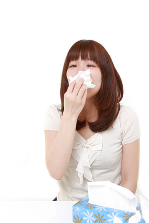 young woman with an allergy sneezing into tissue&#12288;の写真素材