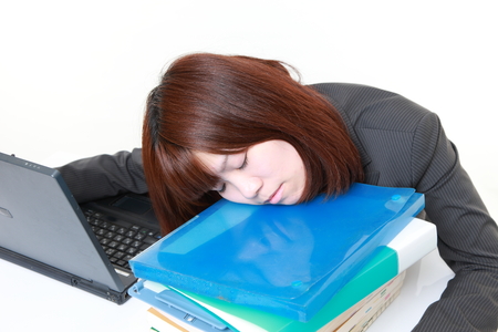 young Japanese businesswoman sleeping on the deskの写真素材