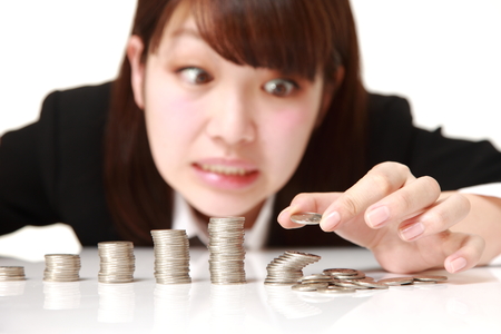 stack of coins collapsed when businesswoman put a coinの写真素材