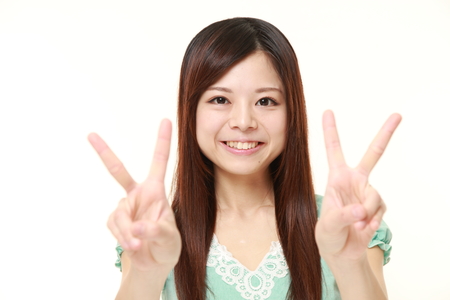 young Japanese woman showing double victory signの写真素材