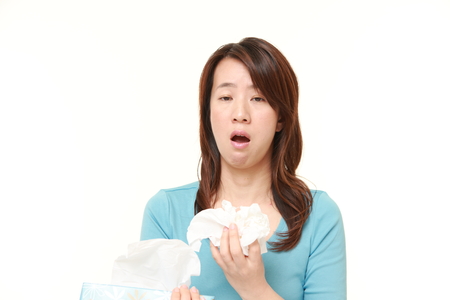woman with an allergy sneezing into tissueの写真素材