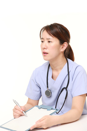 Japanese female doctor with clinical record talks to her patientの写真素材