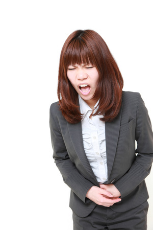 young Japanese businesswoman suffers from stomachacheの写真素材