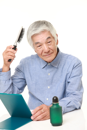 senior Japanese man using hair restorerの写真素材